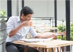 Een man drinkt koffie en leest de krant in een bedrijfstuin